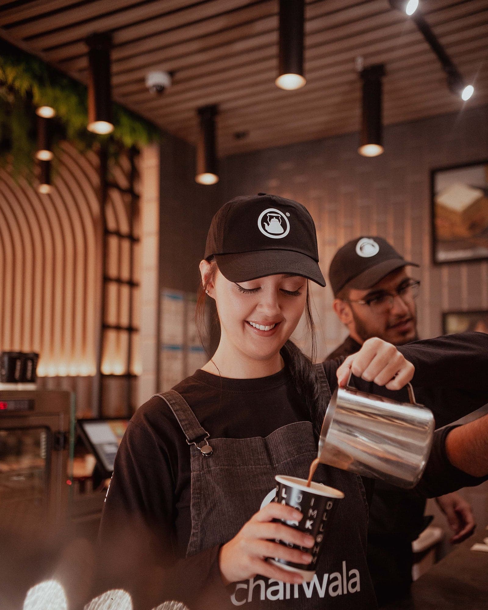 A barista pulling karak chaii